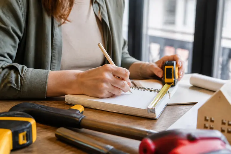 Mains d'une femme française mesurant avec précision pour une simulation-dpe, notant les détails cruciaux.