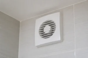 Gros plan sur une bouche VMC de salle de bain moderne, installée près du plafond.