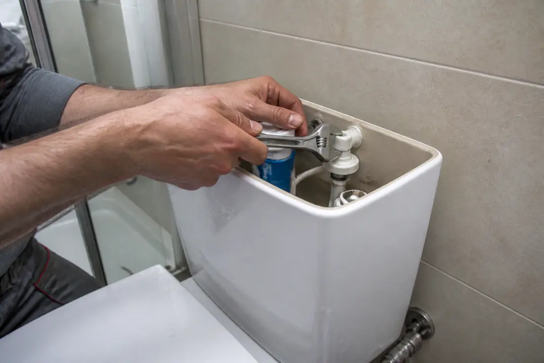 Intervention sur un mécanisme de WC alors qu'une chasse d'eau coule en continu dans une salle de bains