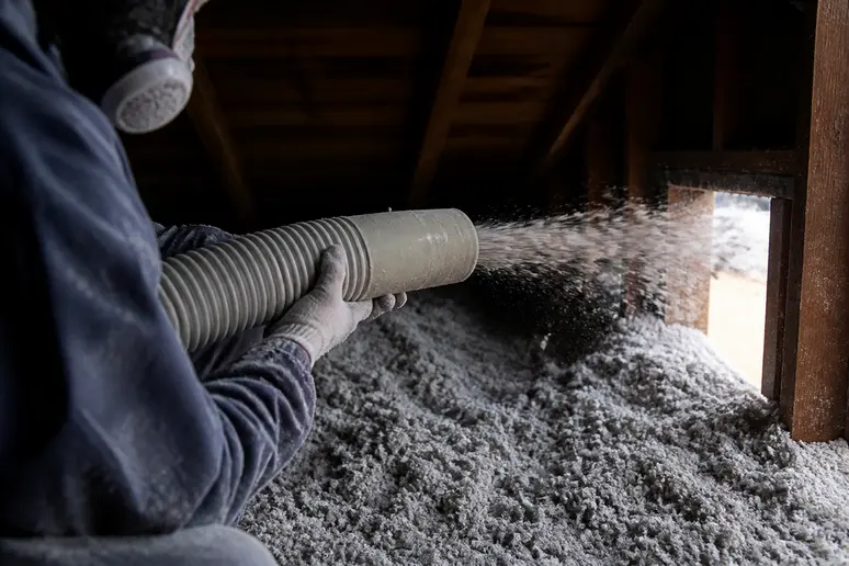 Application de ouate de cellulose en vrac dans des combles perdus par soufflage.