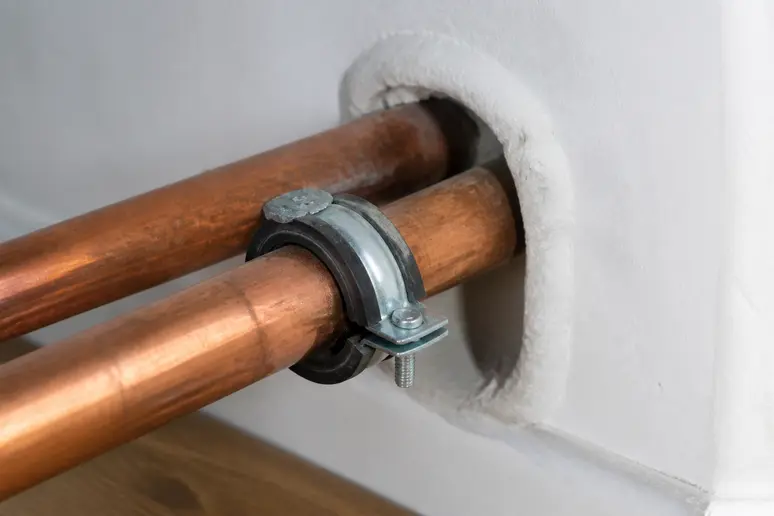 Tuyau de chauffage traversant une cloison maintenu par un collier isophonique adapté