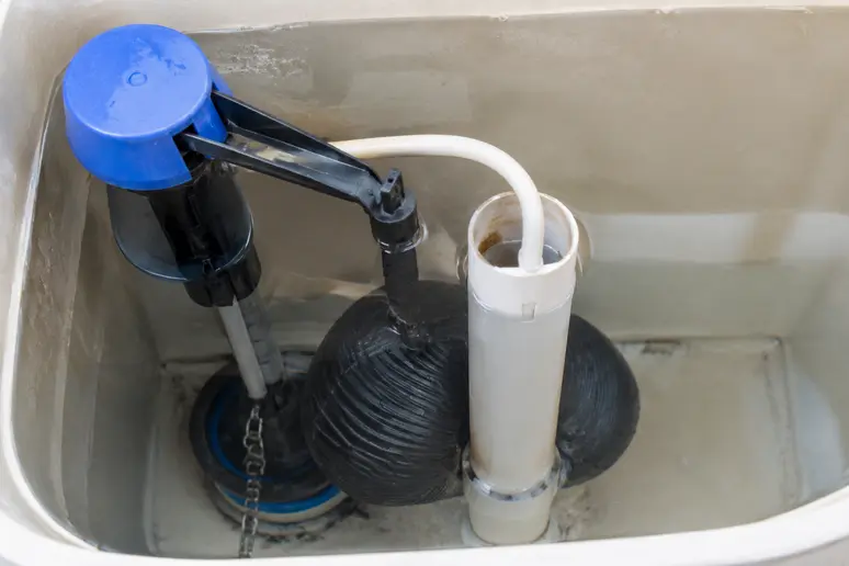 Flotteur de chasse d'eau bloqué au fond du réservoir à côté du tube de trop-plein