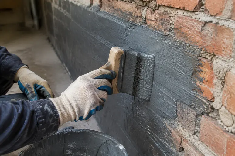 Application à la brosse d'un enduit de cuvelage sur un mur de cave brut
