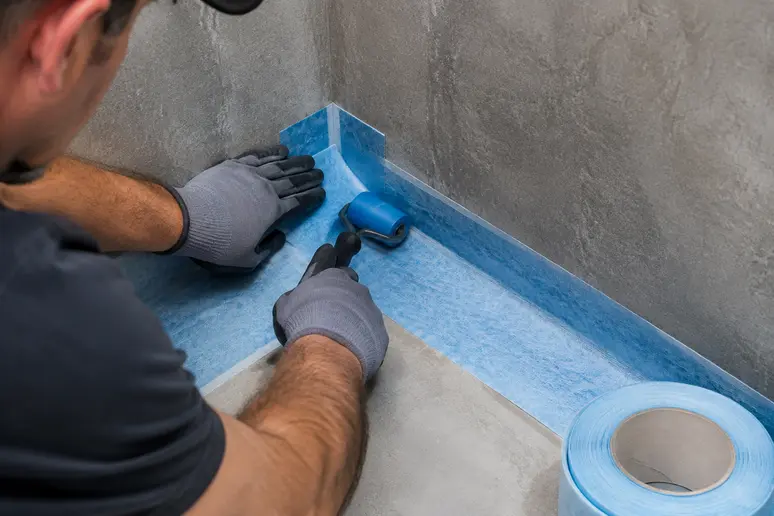 Mise en place d'une bande de renfort pour l'étanchéité sous carrelage dans l'angle d'une douche