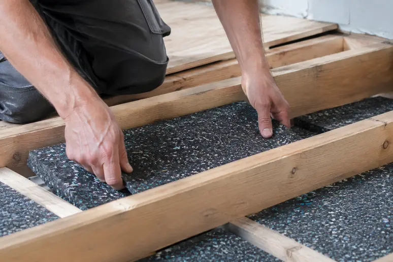 Pose de plots résilients sous des lambourdes pour réaliser une isolation acoustique sol efficace.