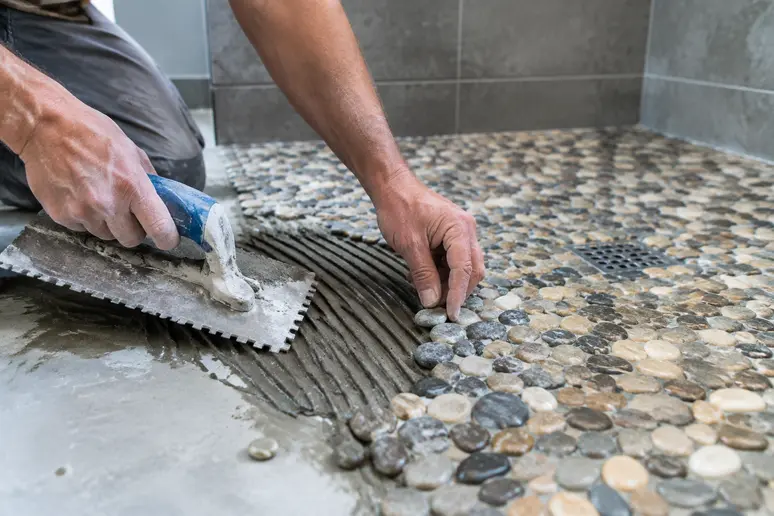 Pose de galets sur une pente de douche italienne avec du mortier