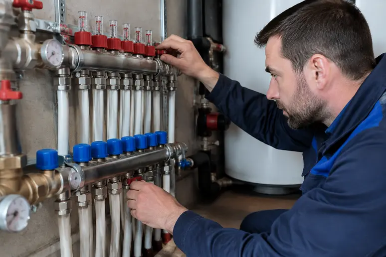 Technicien ajustant les vannes du collecteur pour le réglage de la température de départ et de retour