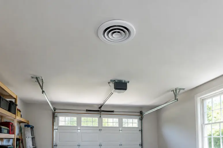 Bouche d'extraction d'une ventilation installée au centre du plafond d'un garage.