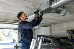 Technicien installant un système de vmc garage au plafond avec une perceuse