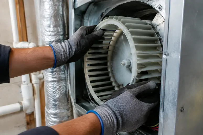 Mains faisant tourner manuellement la turbine d'une VMC pour identifier un défaut de condensateur
